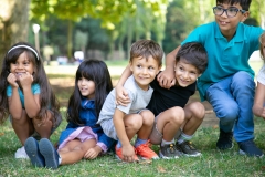 Cheerful kids sitting and squatting down on grass