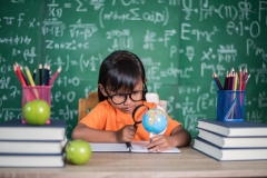 kid observing or studying educational globe model in the classroom.